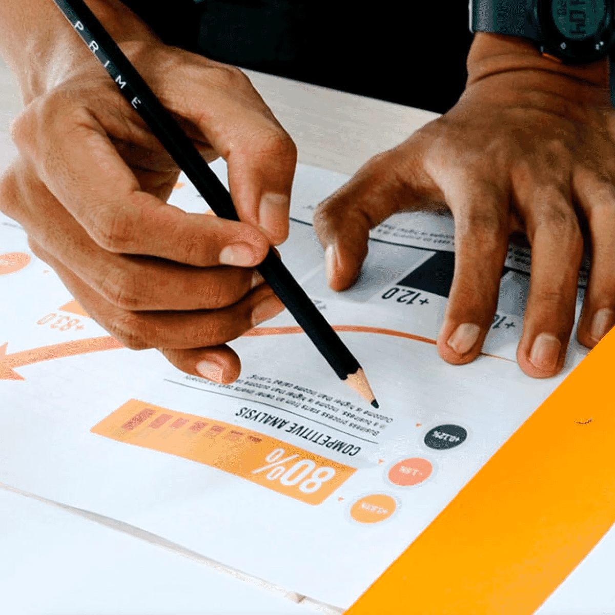 hands of person with light brown skin holding a pencil above sheets of paper with diagrams on it