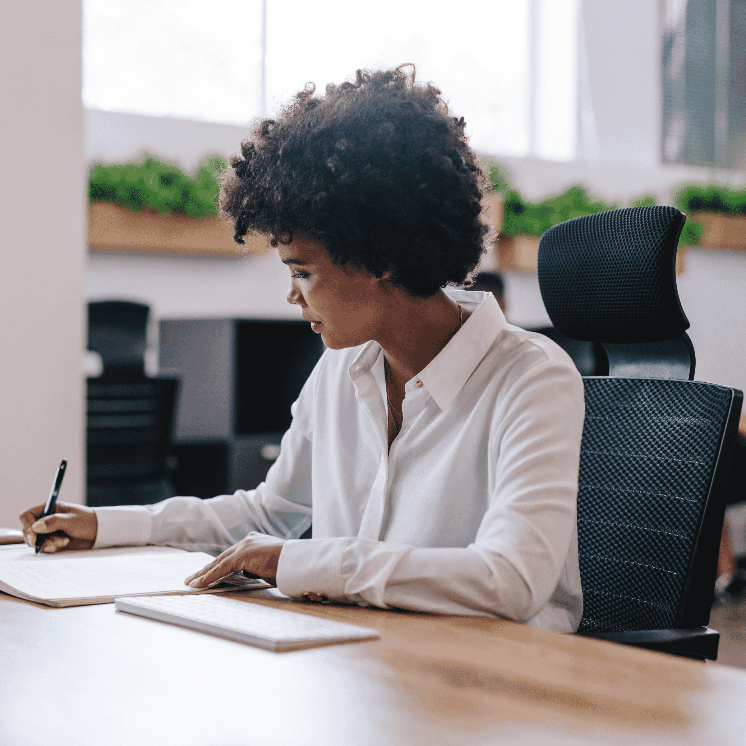 woman writing on paper at office desk