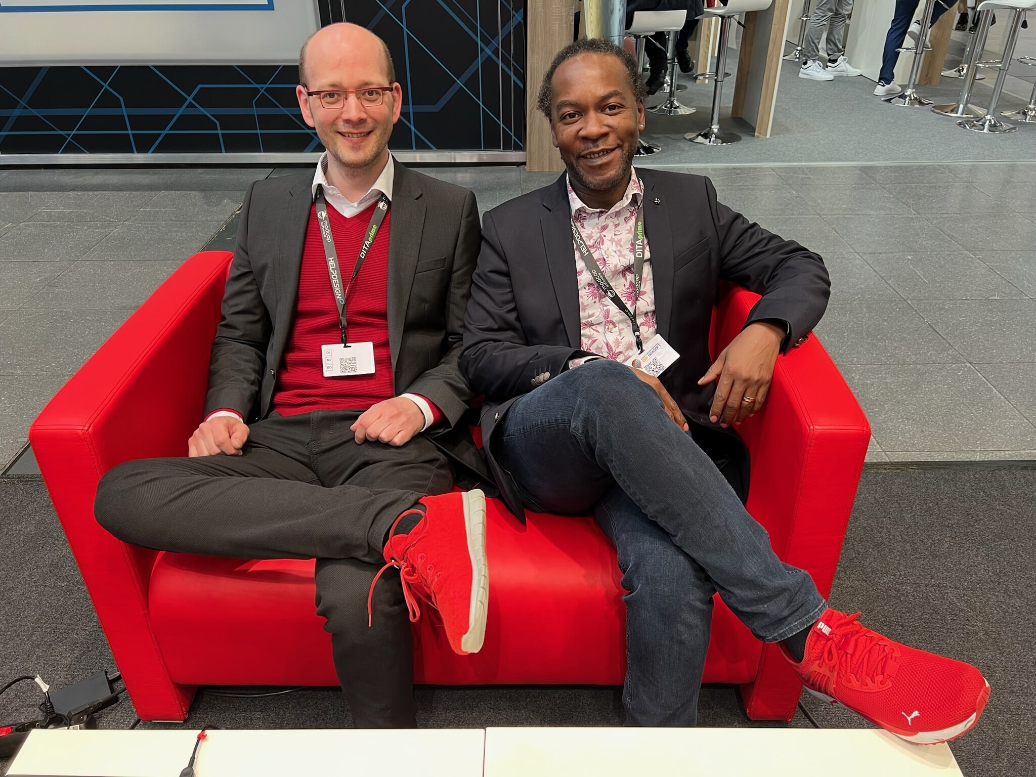 MadCap team memebers Andreas and Dipo sitting on a red chair with matching red sneakers