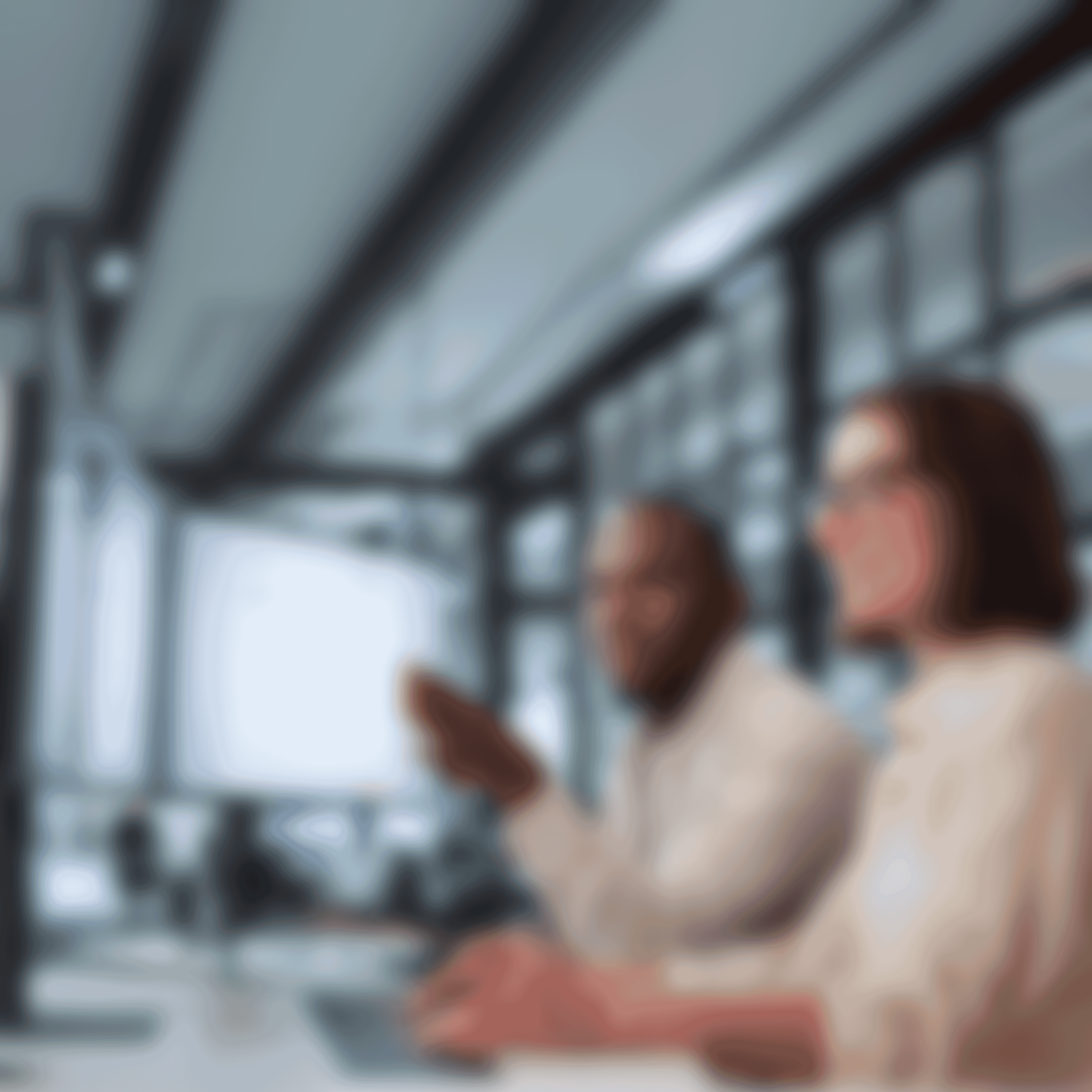 Sitting at a professional tech workspace with dual-monitor set, two technical writers are reviewing structured documentation.