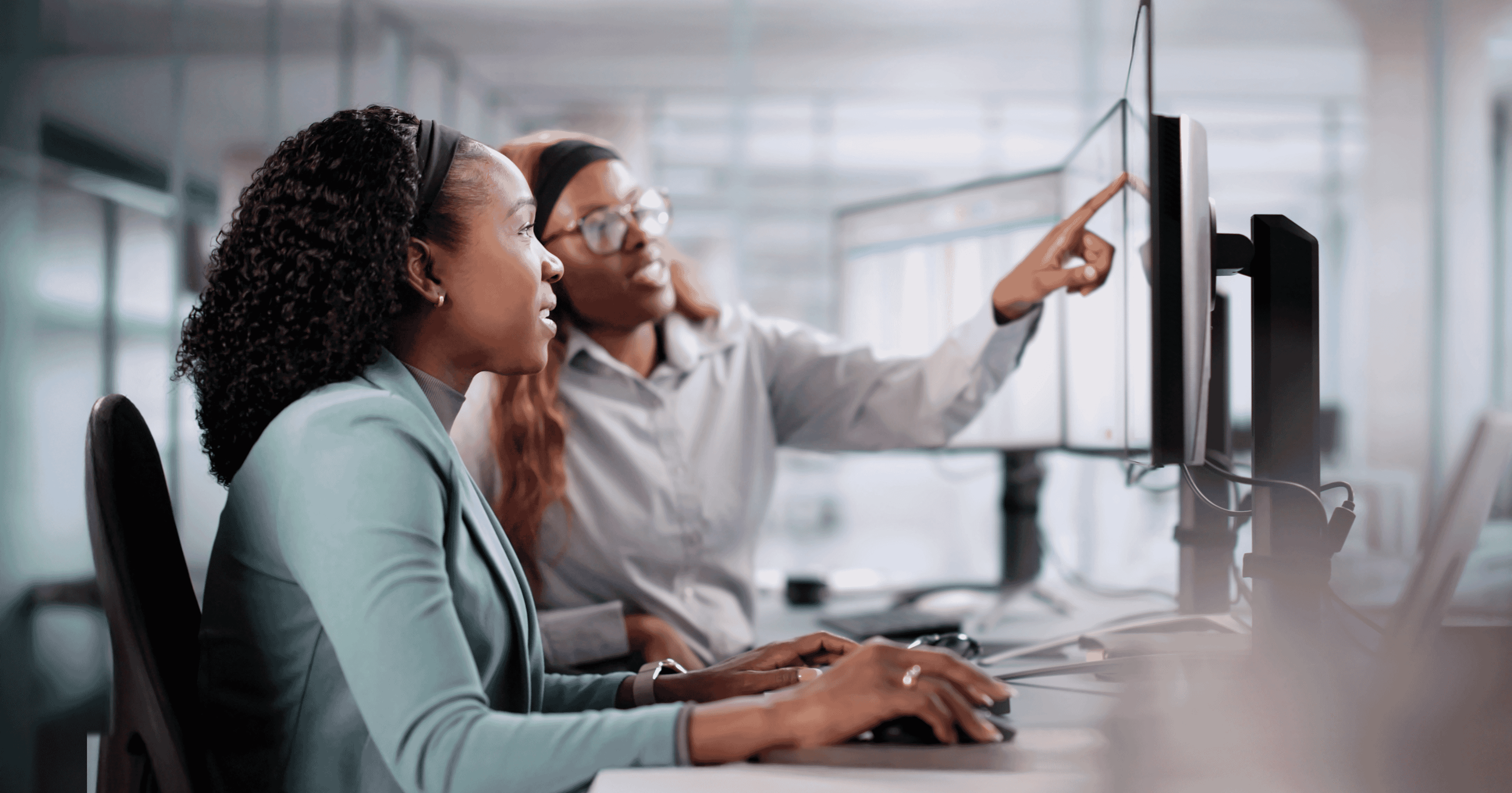Photo of two women collaborating at work in front of a computer.