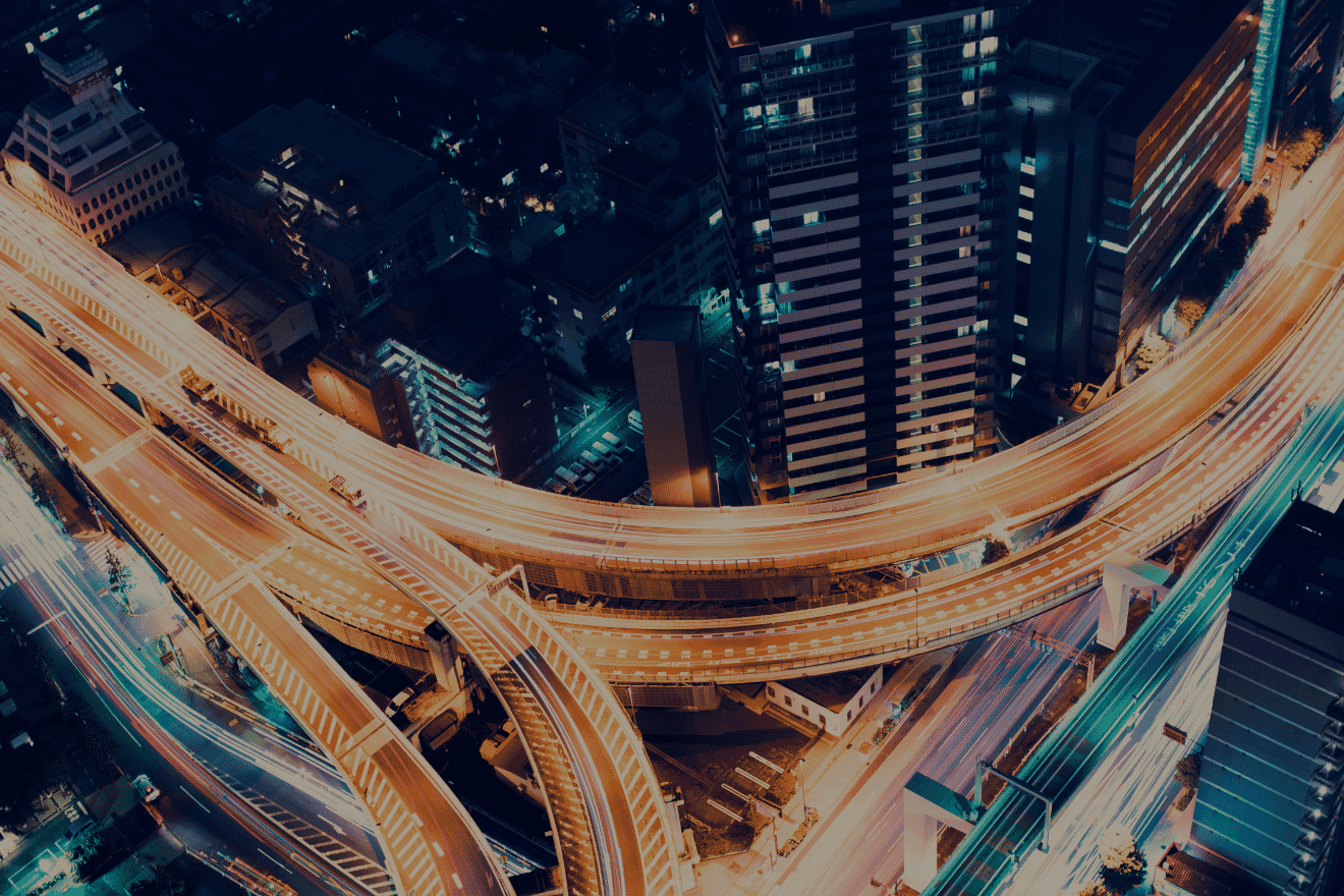 Aerial nighttime view of urban highway interchange and city skyline