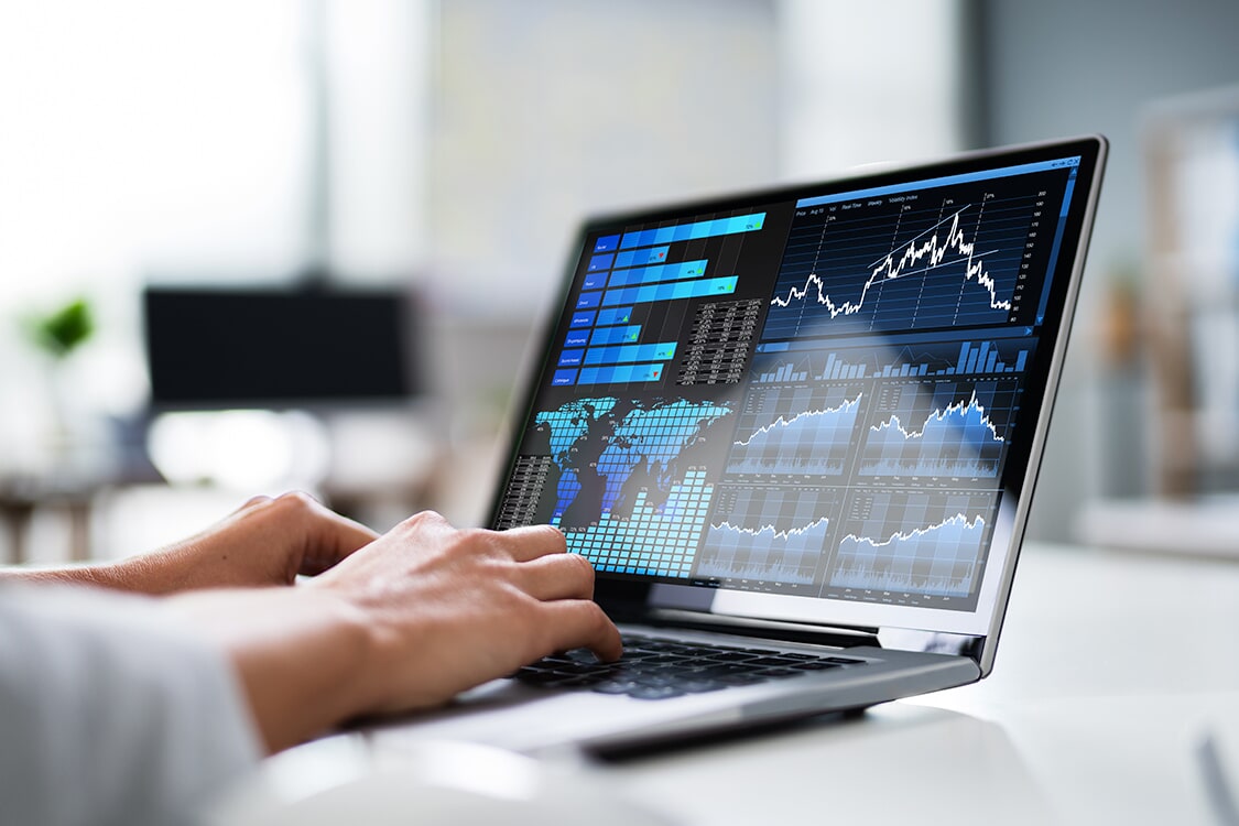 Hands on a laptop displaying a data dashboard with charts and graphs