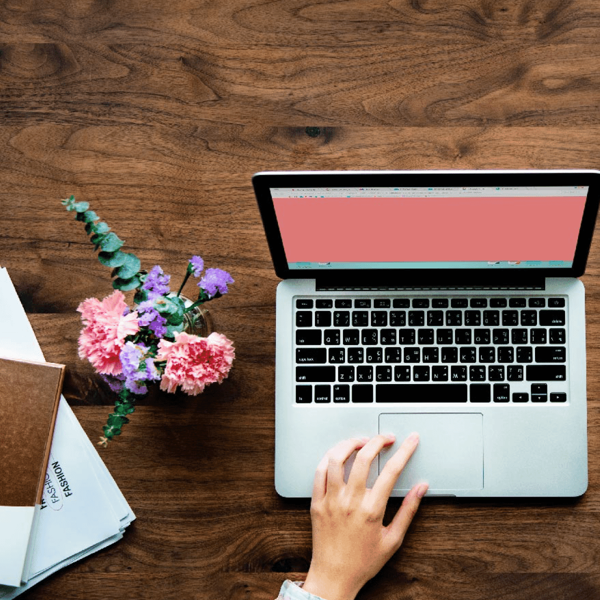 Overhead shot of woman scrolling with one hand and coffee in the other with her phone, flowers, and paperwork on the side