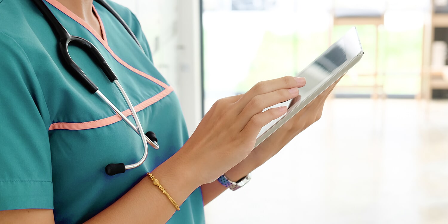 Medical staff member using tablet and laptop