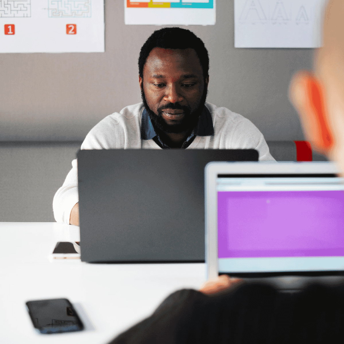 African american man sitting at a table on his laptop across from another man