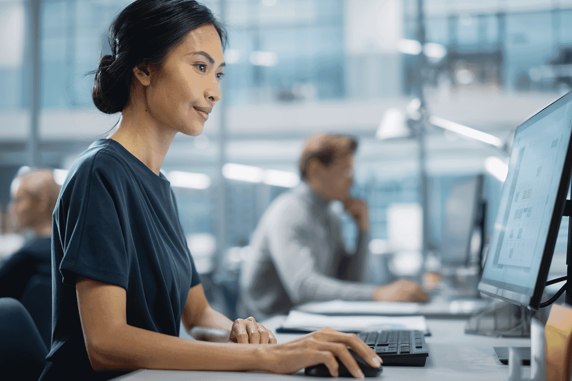 Woman typing at a desktop computer in a modern office