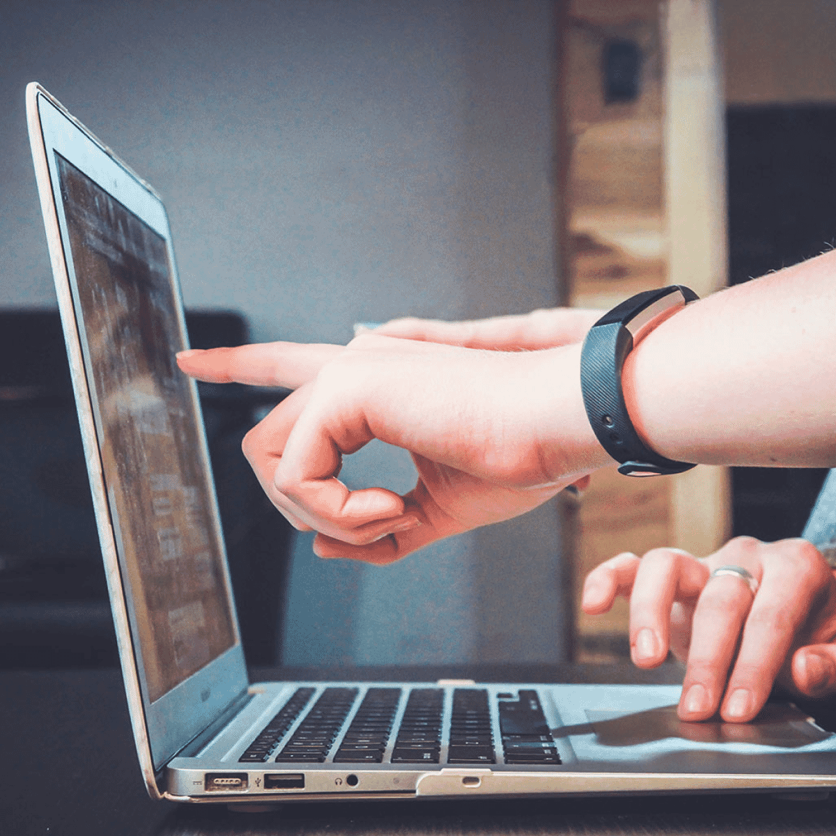 People pointing at laptop screen.