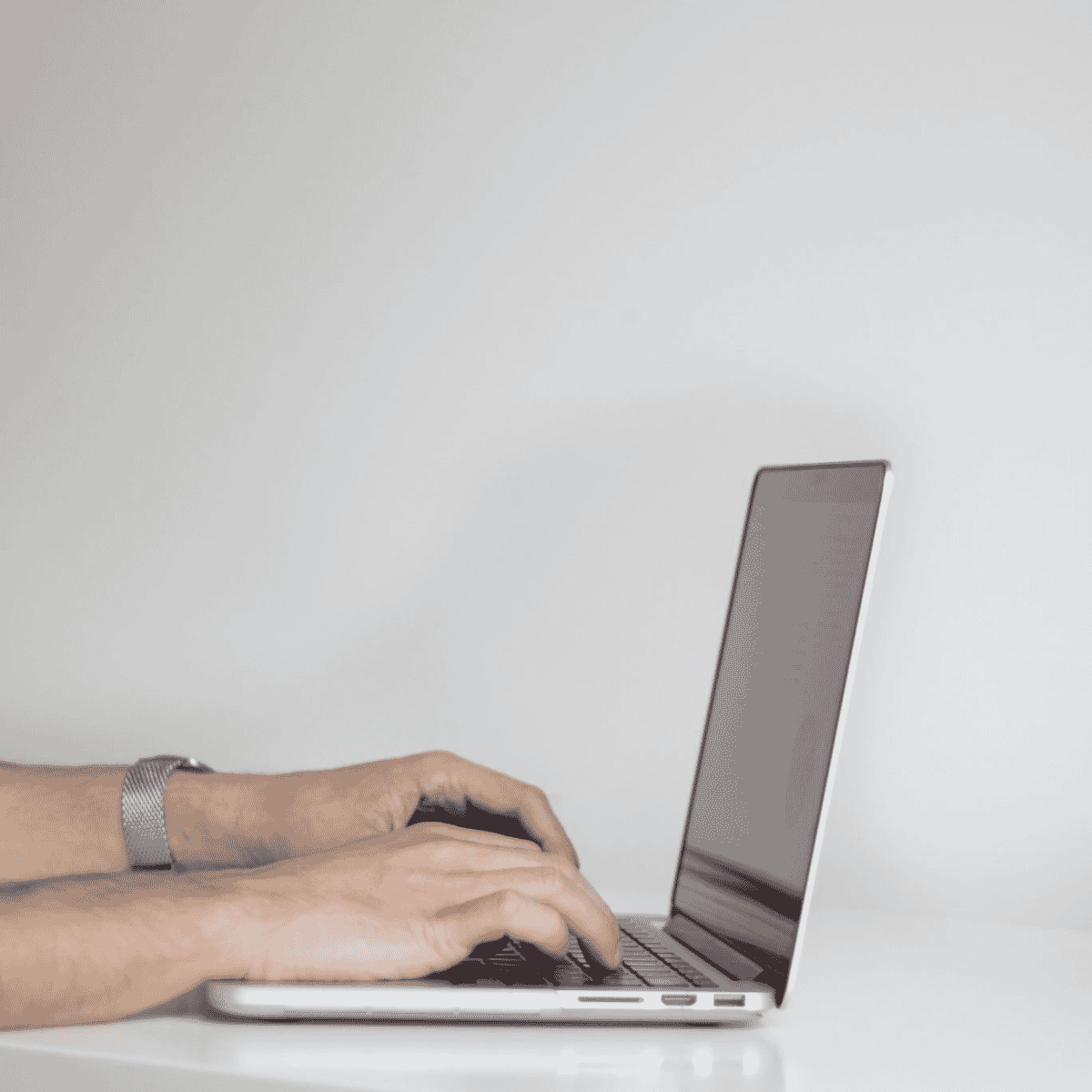 Person typing on laptop with plant.