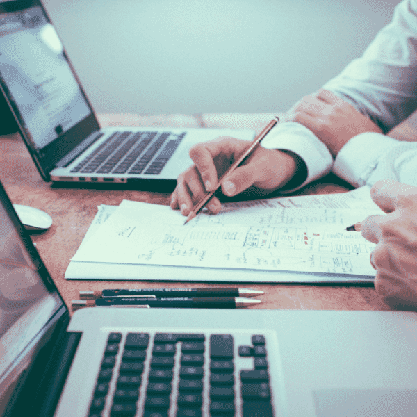 Two people sitting side by side with their laptops going over their notes