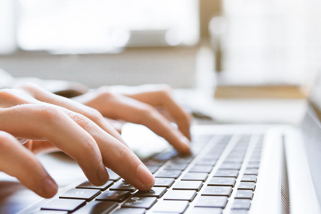 Hands typing on a laptop keyboard
